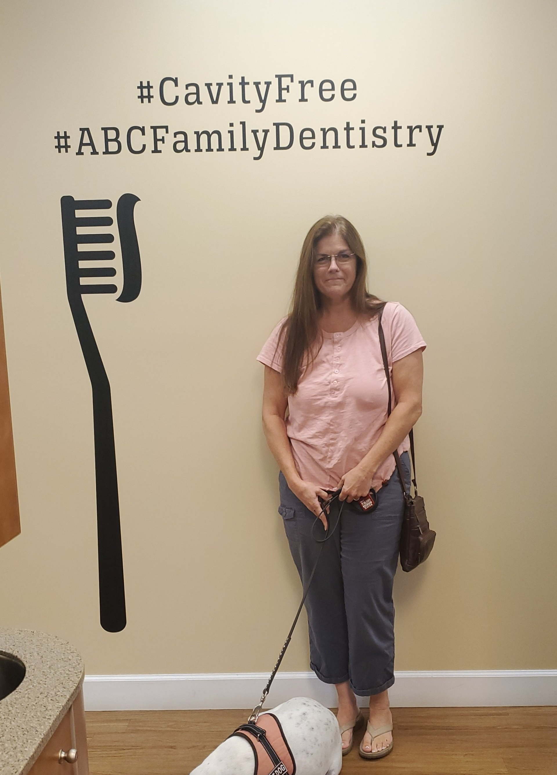 Woman standing with a dog in a dentist's office. A toothbrush and text 