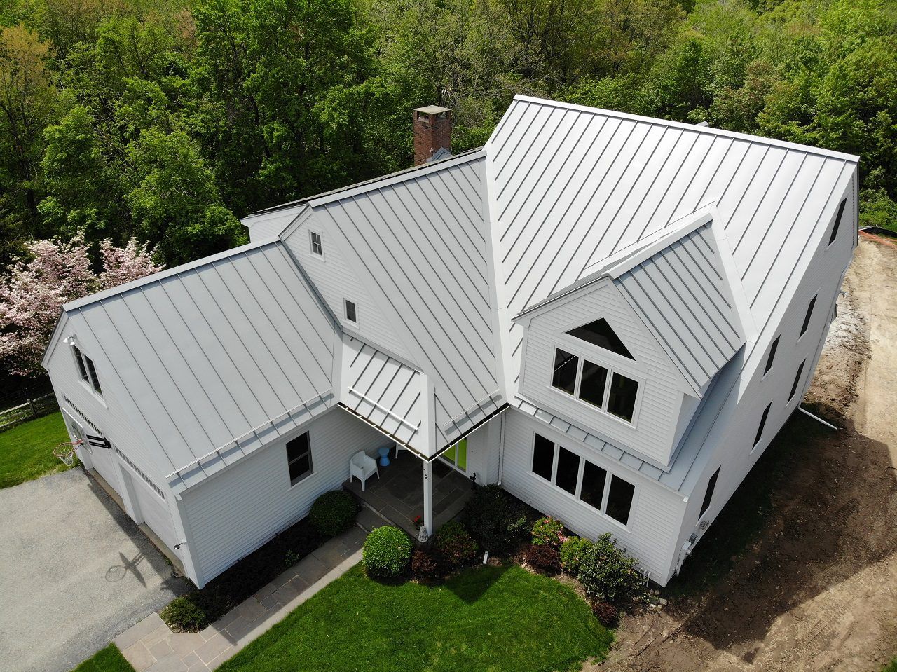 Gutter with black mesh guard installed below gray shingle roof. Clips hold the guard in place.