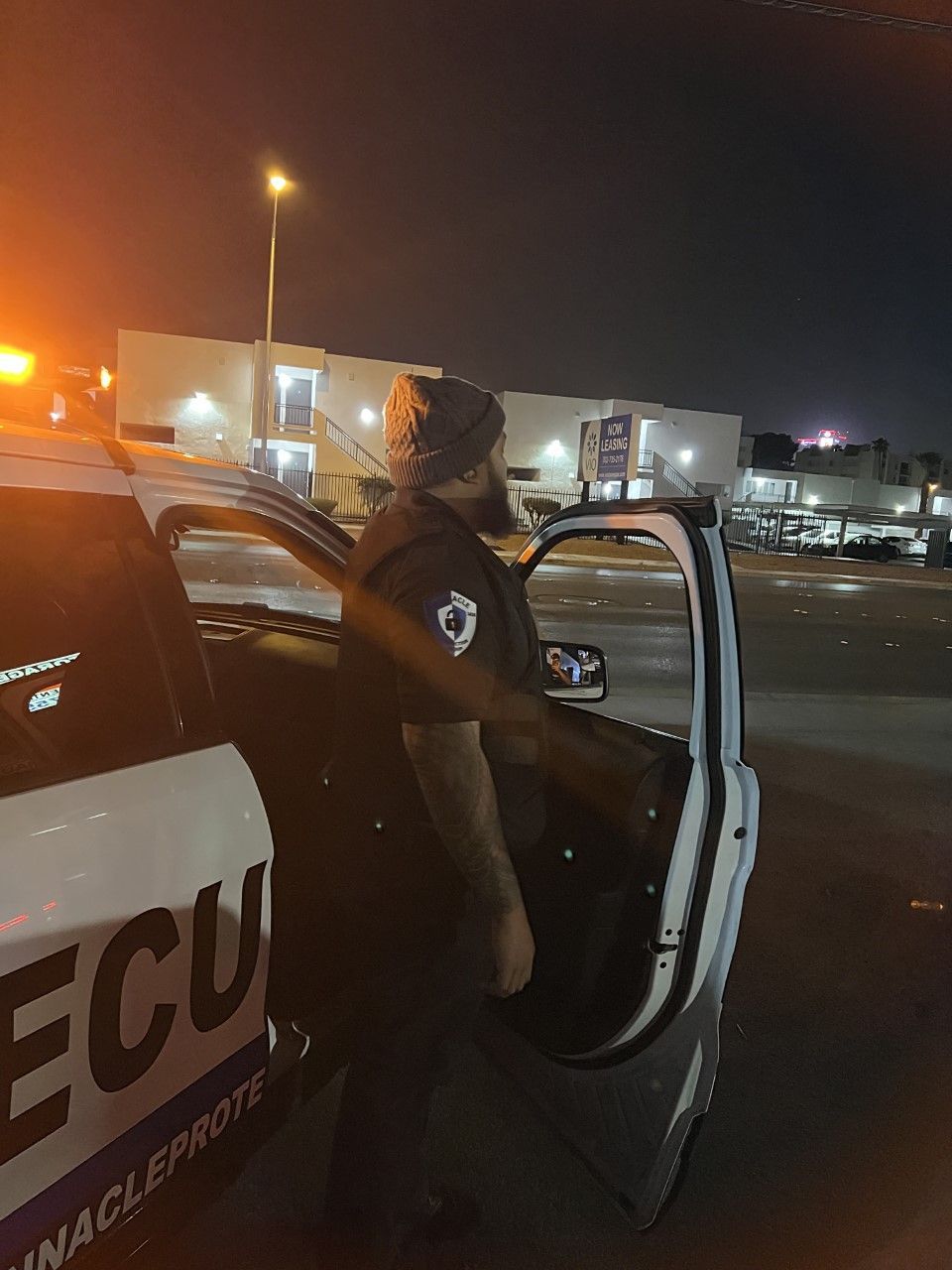A police officer is getting out of a police car at night