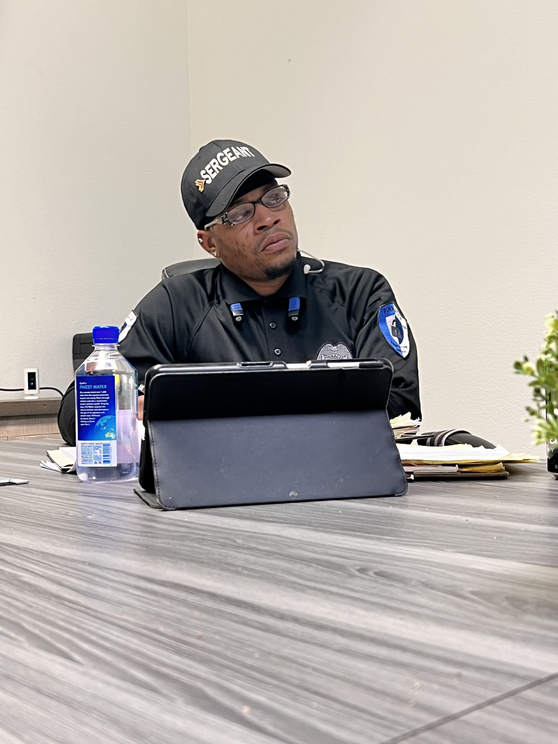 A man in a security uniform is sitting at a table with a tablet.