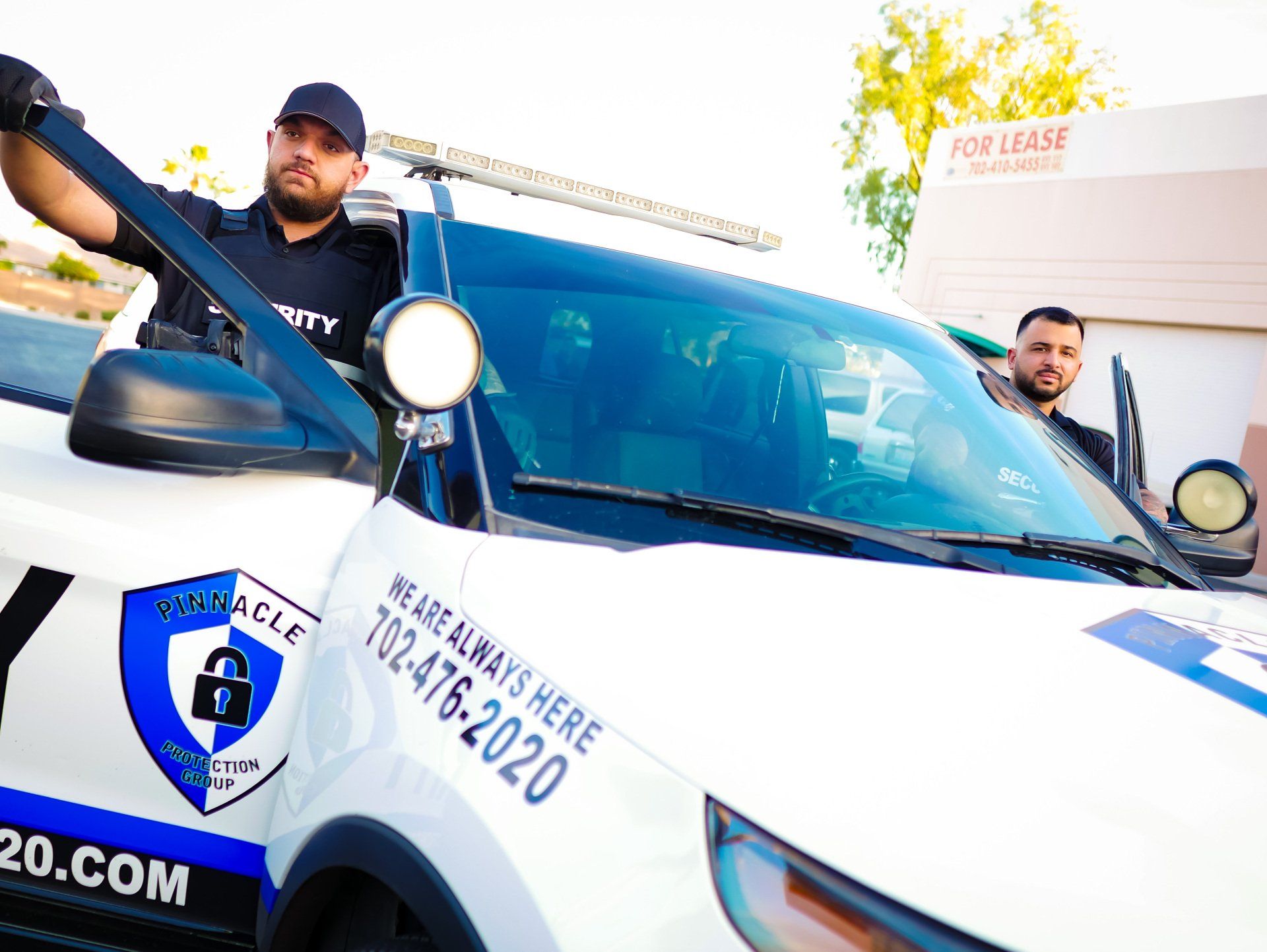two men are standing next to a security vehicle .