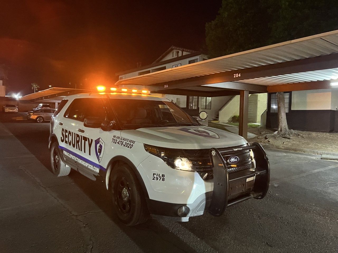 A security vehicle is parked in front of a building at night.