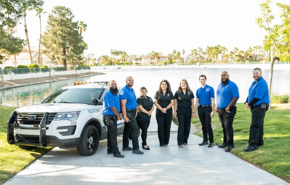 A group of police officers and a police vehicle pose near a lake.
