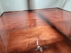 Shiny copper-colored floor with water or liquid pooled in a corner near white walls