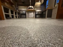 Low-angle view of a speckled kitchen floor with cabinets and stainless steel appliances in the background