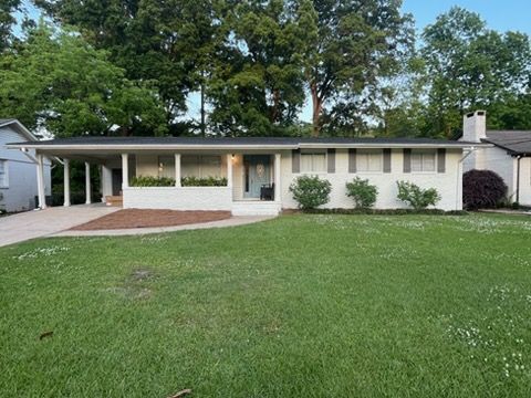Single-story white house with a covered carport and a large green lawn in front