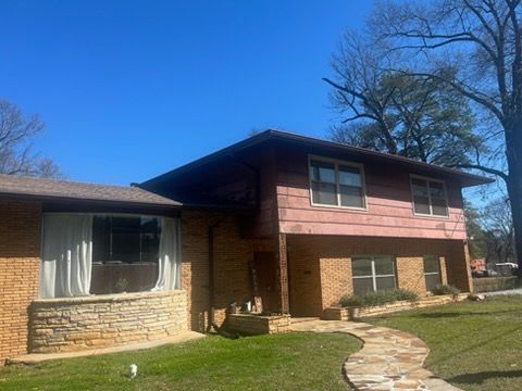 Suburban split-level house with brick and wood exterior, large front window, and curved stone walkway