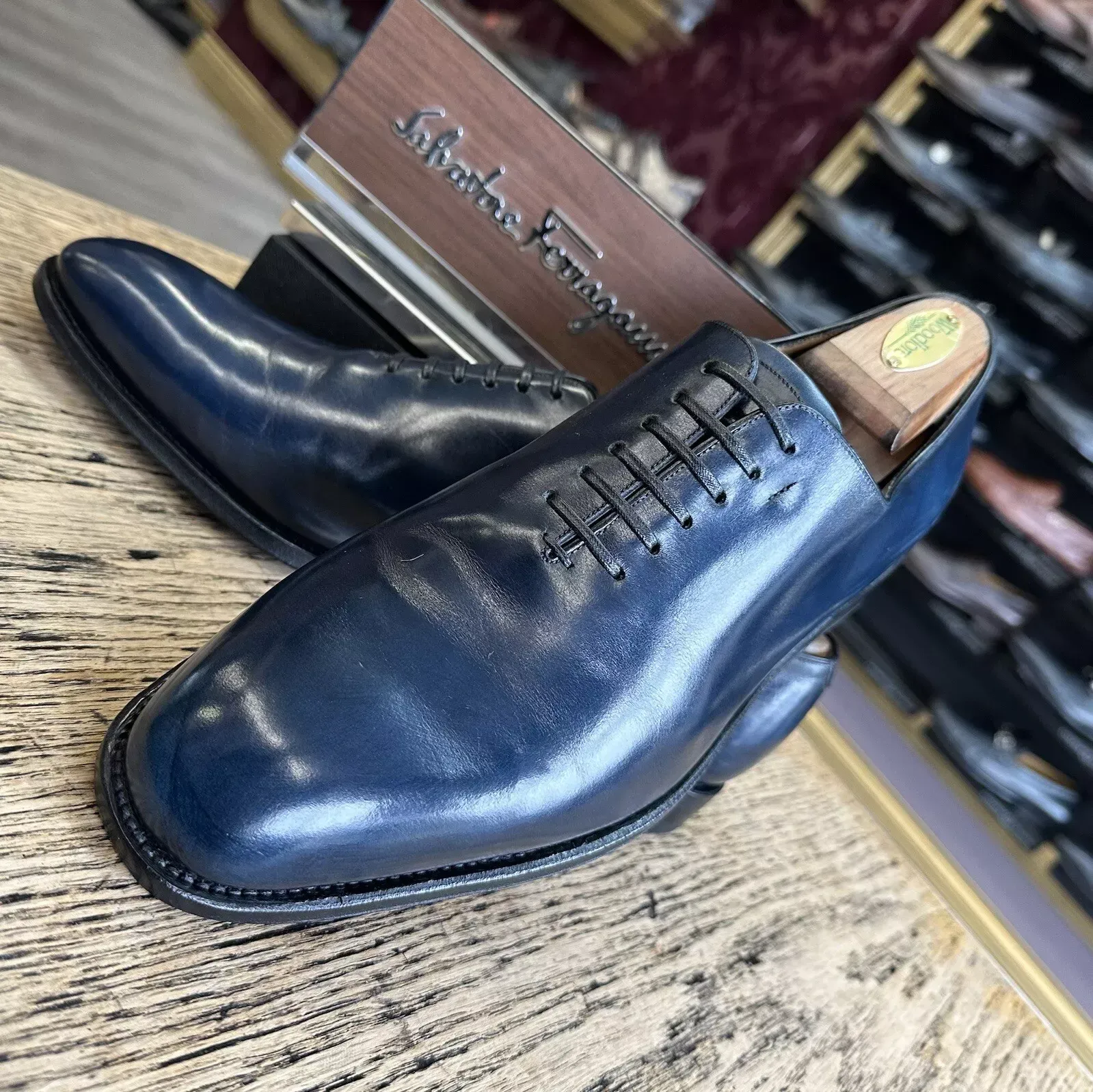 A pair of blue ferragamo shoes are sitting on a wooden table.