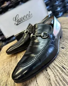 A pair of black gucci loafers are sitting on a wooden table.