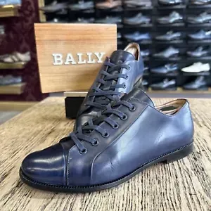 A pair of blue bally shoes are sitting on a wooden table.