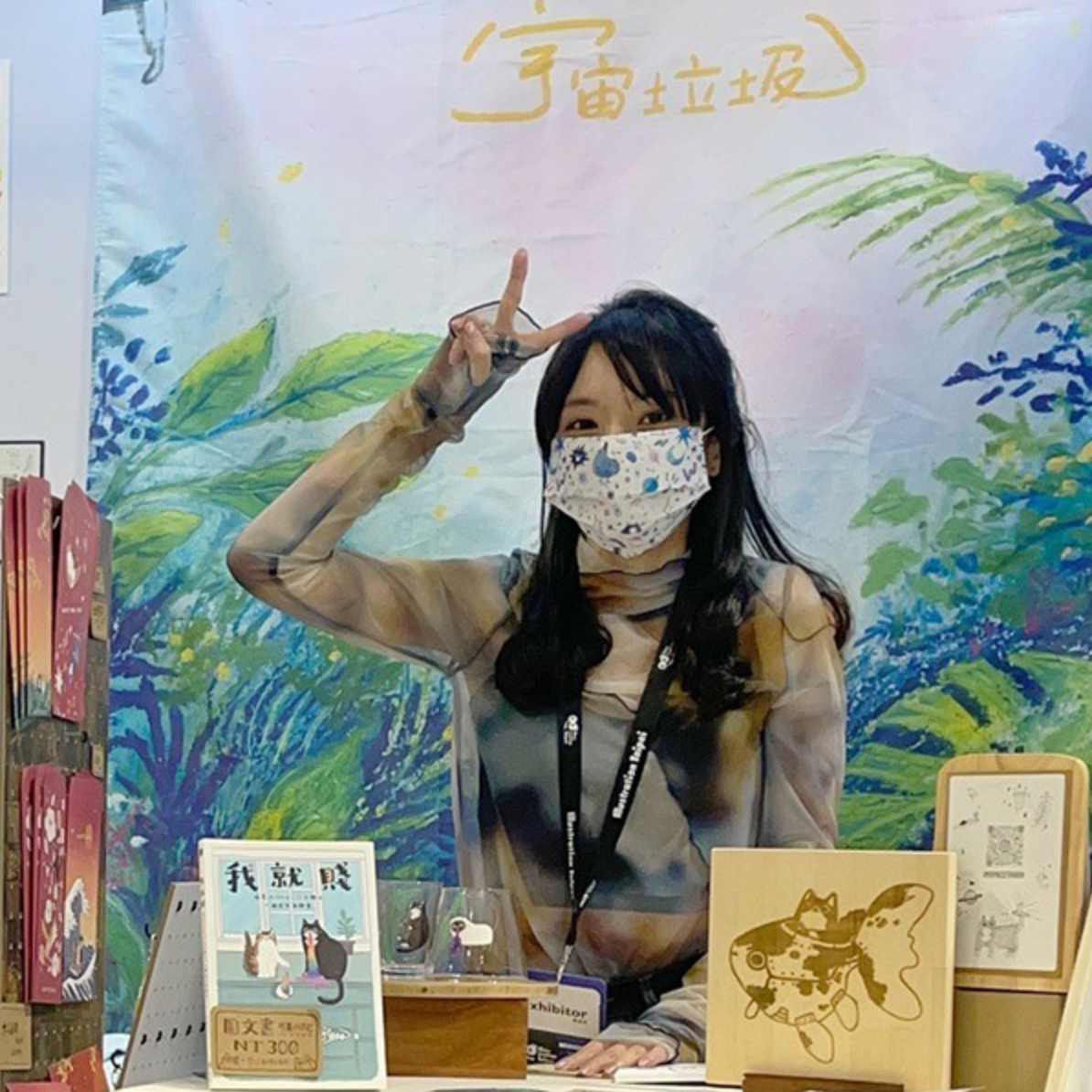 一名戴著口罩的女性站在有大型插畫的牆前