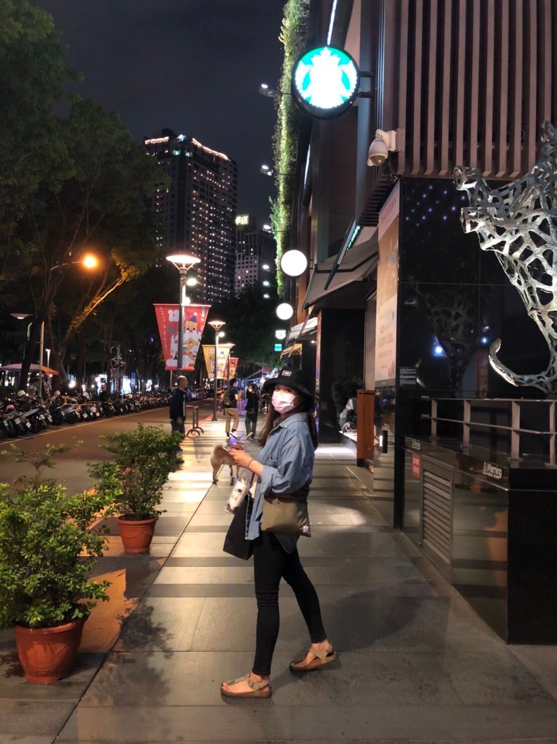 一位戴著口罩的女性正走在人行道上,經過一家咖啡店