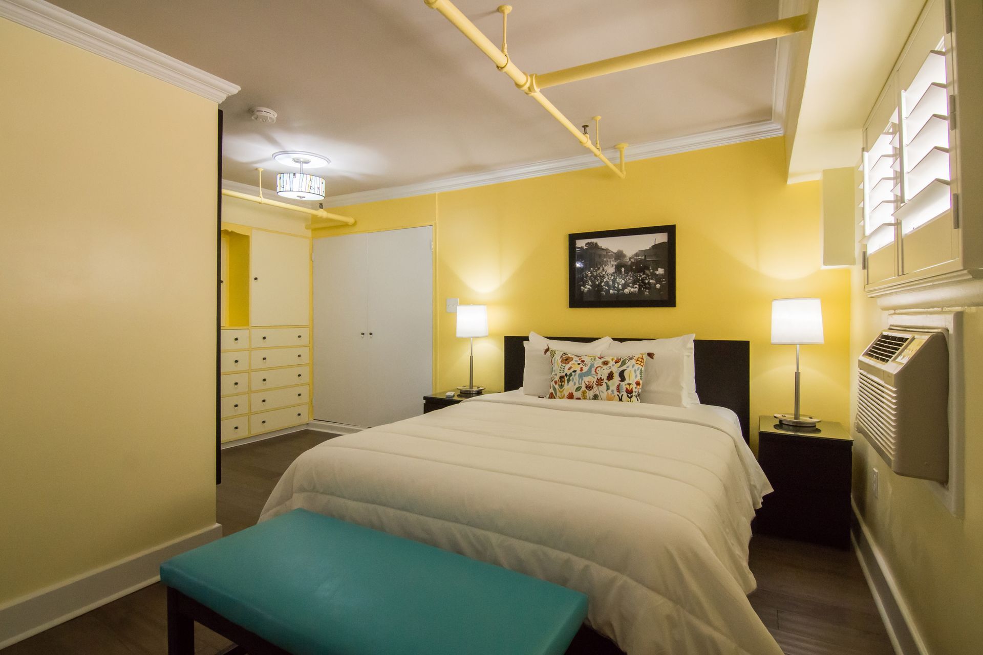 A hotel room with a king size bed and a blue bench.
