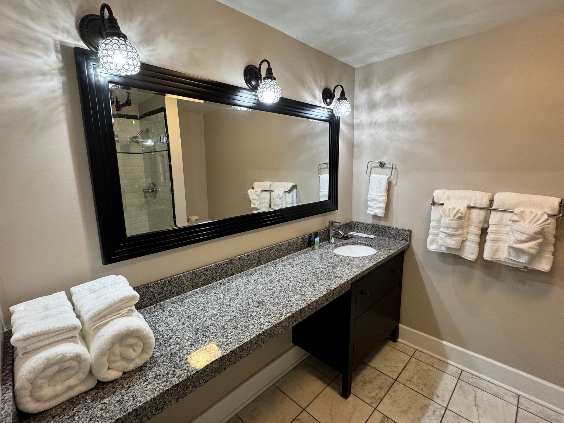 A bathroom with a sink , mirror and towels on the counter