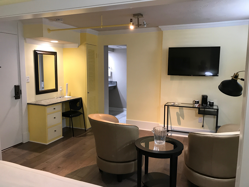 A hotel room with two chairs and a flat screen tv.