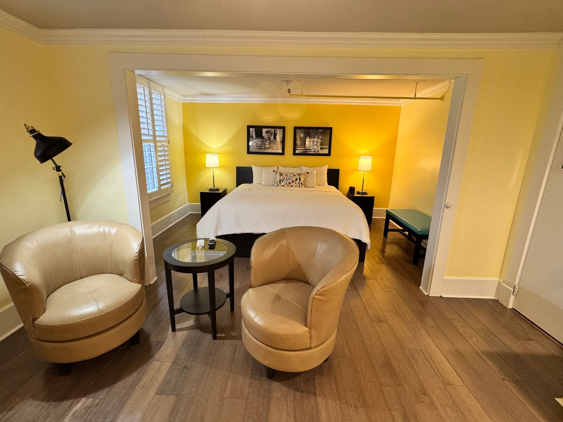 A bedroom with a bed , two chairs , a table and a lamp.