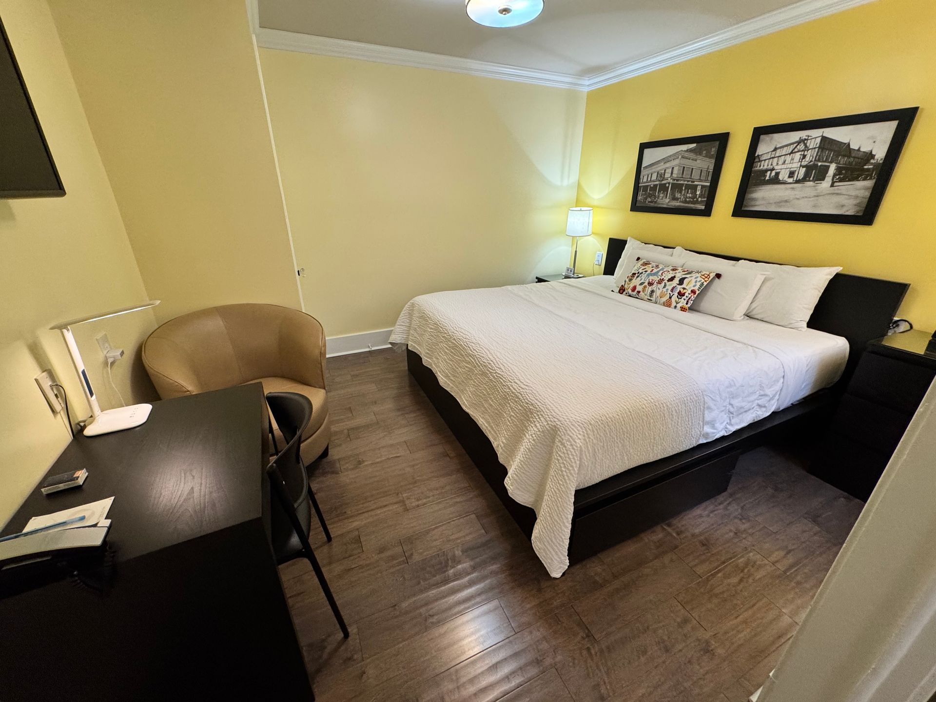 A hotel room with a bed , chair , desk and television.