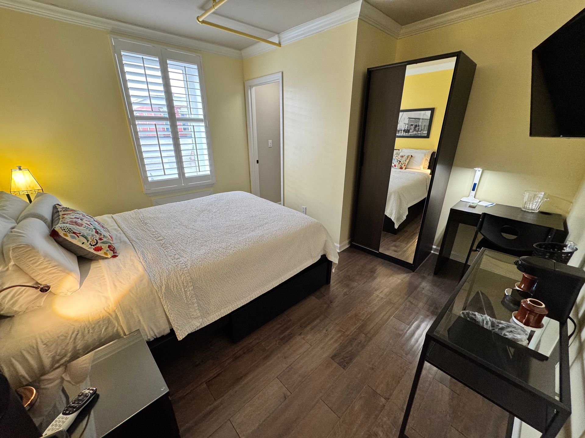 A hotel room with a bed , desk , mirror and television.