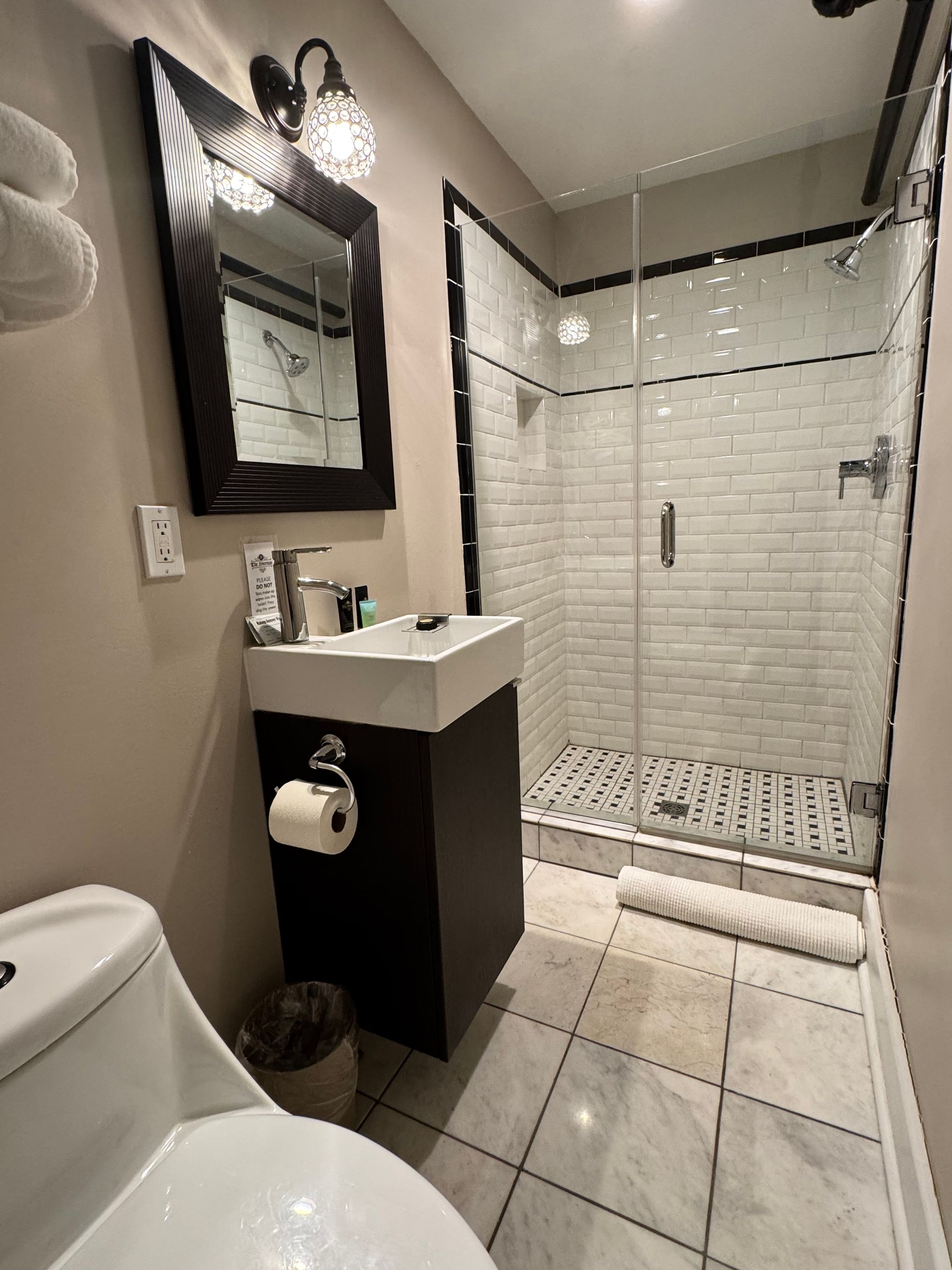A bathroom with a toilet , sink , mirror and shower.