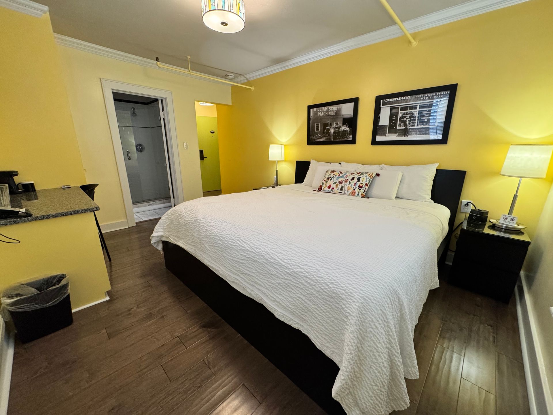 A hotel room with a king size bed and yellow walls