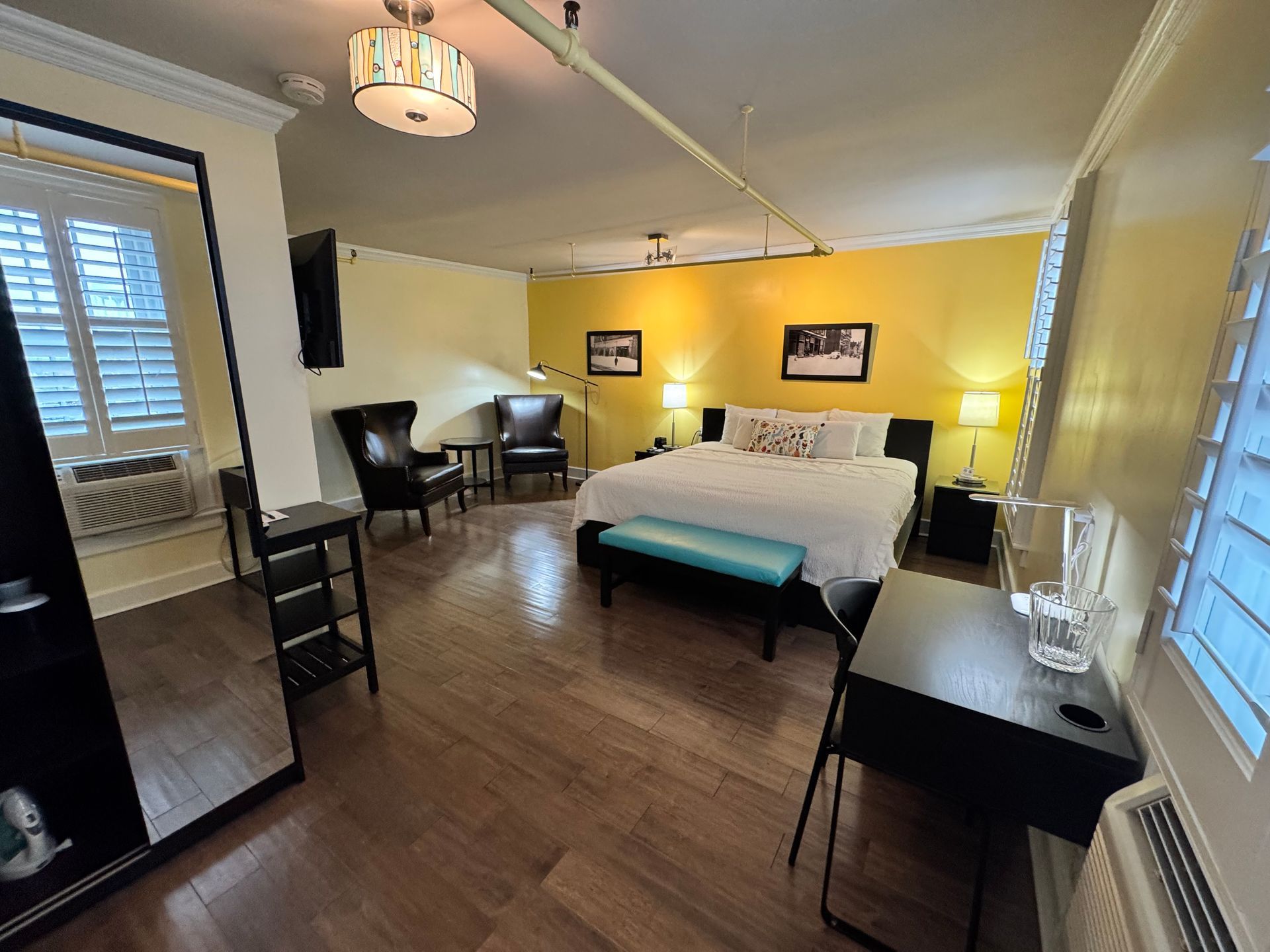 A hotel room with a large bed , desk , chairs and a large mirror.