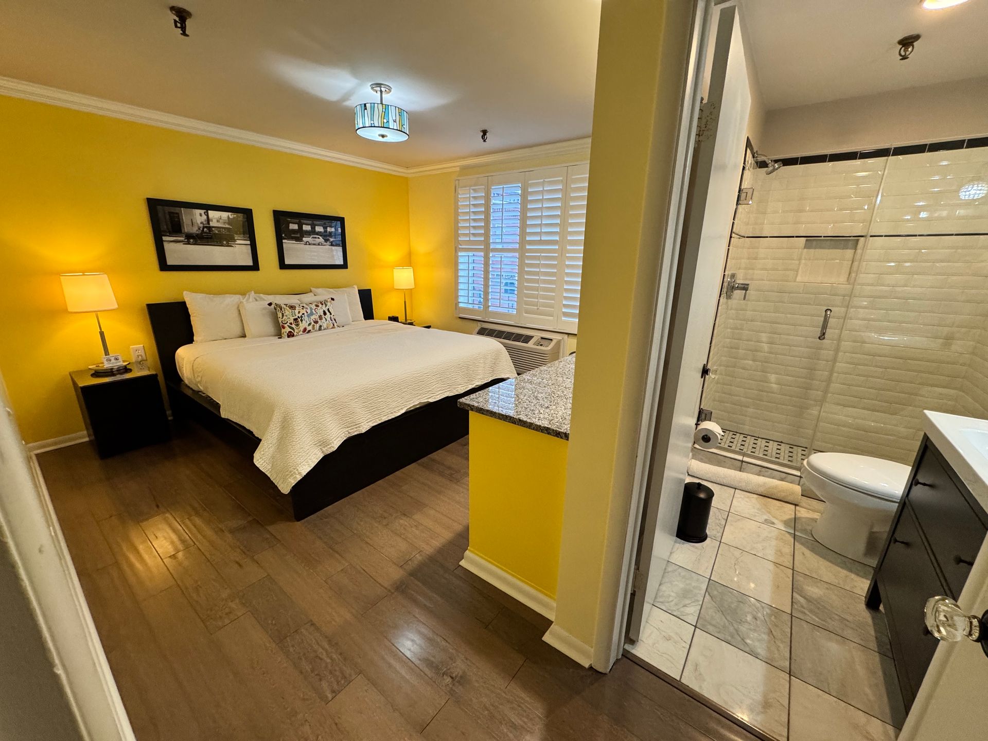 A bedroom with a king size bed and a bathroom with a walk in shower.