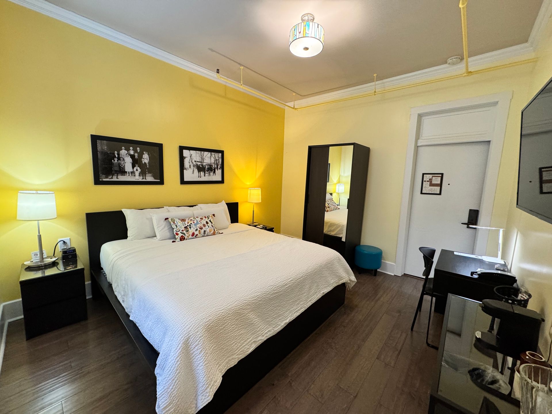 A hotel room with a king size bed and yellow walls