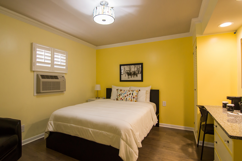 A hotel room with a king size bed and yellow walls.