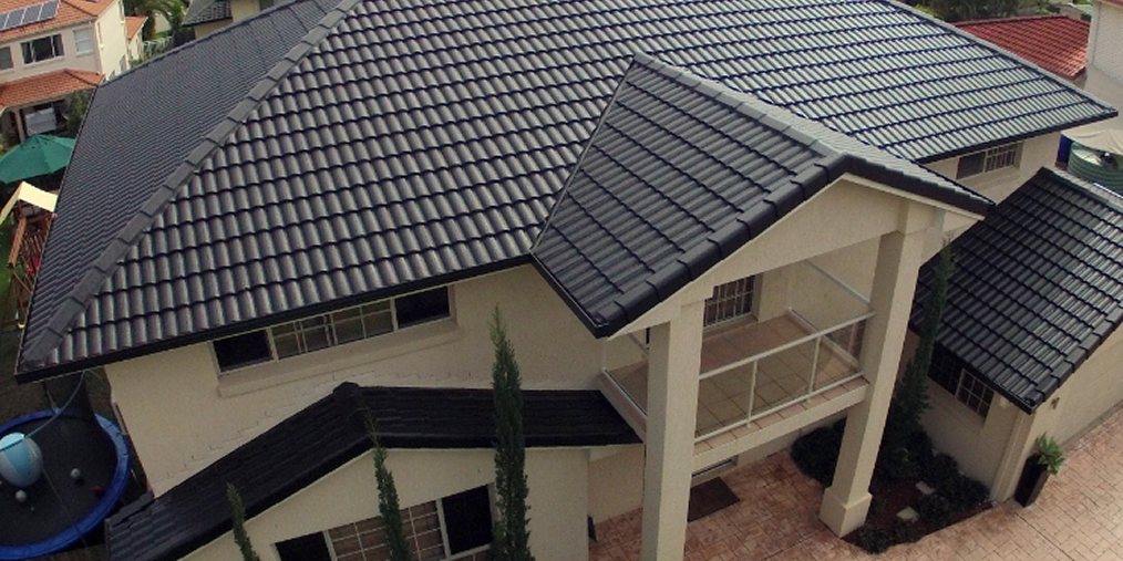 An aerial view of a large house with a black roof.