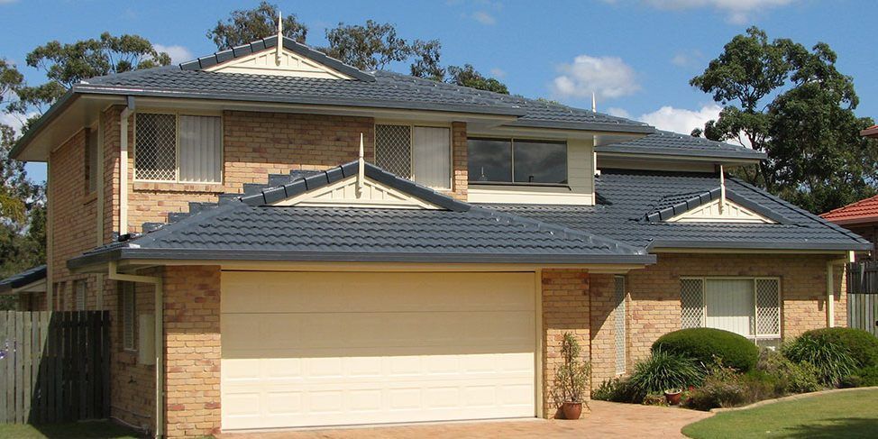 A brick house with a white garage door and a blue roof