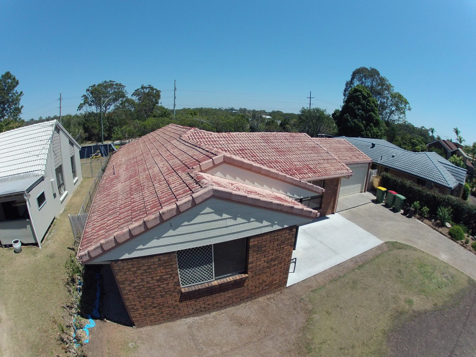 An aerial view of a brick house with a red tiled roof