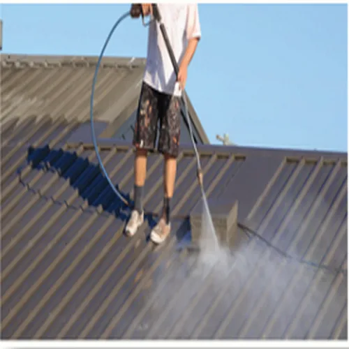 A man is cleaning a roof with a high pressure washer
