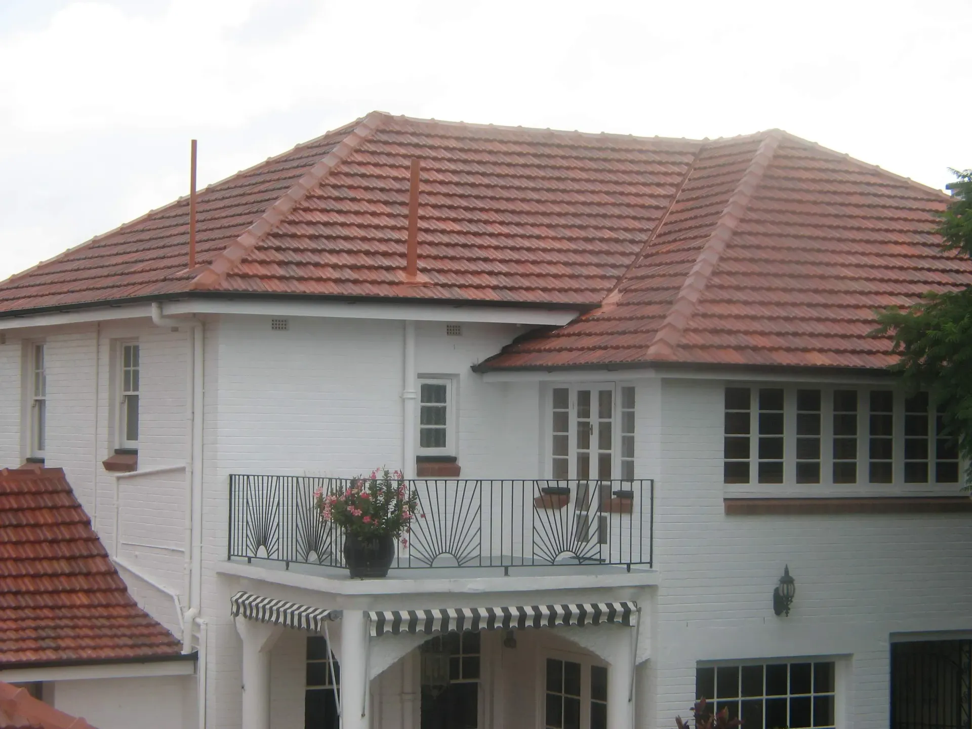 A white house with a red tiled roof and a balcony