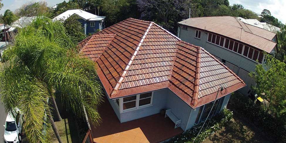 An aerial view of a house with a tiled roof surrounded by trees.