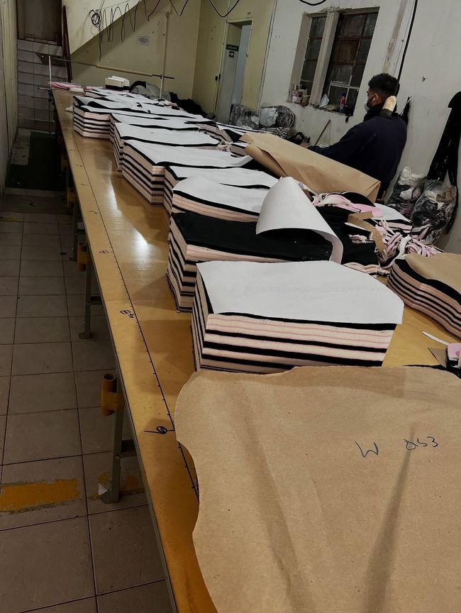 Montones de telas o prendas de vestir a rayas dobladas y dispuestas sobre una larga mesa de trabajO