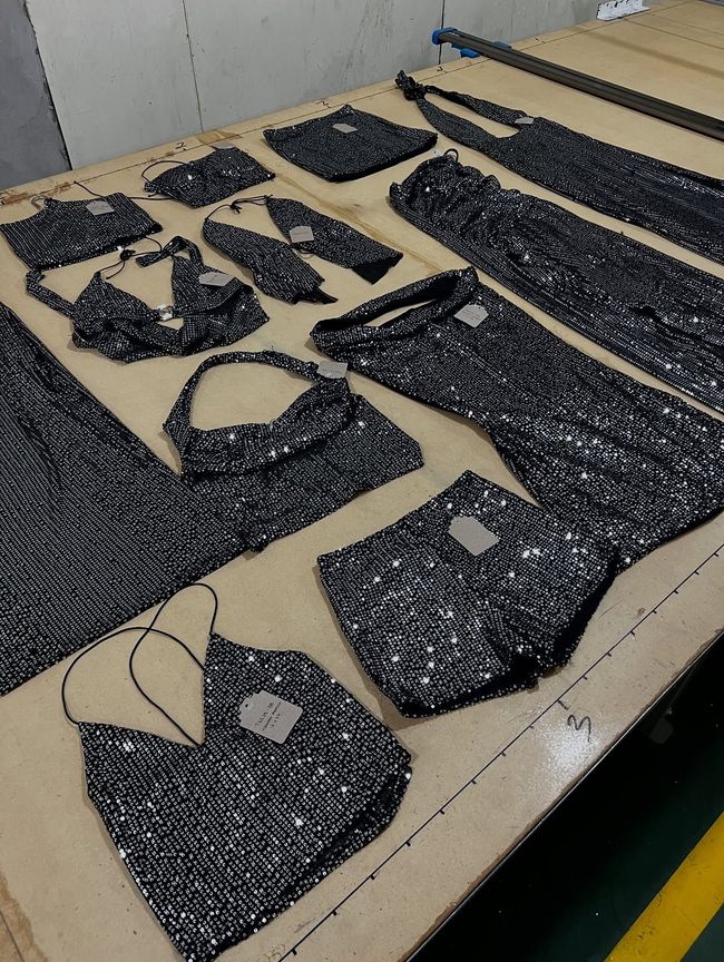 Piezas de tela cortadas para prendas de vestir, dispuestas sobre una mesa de trabajo en un taller de costura.