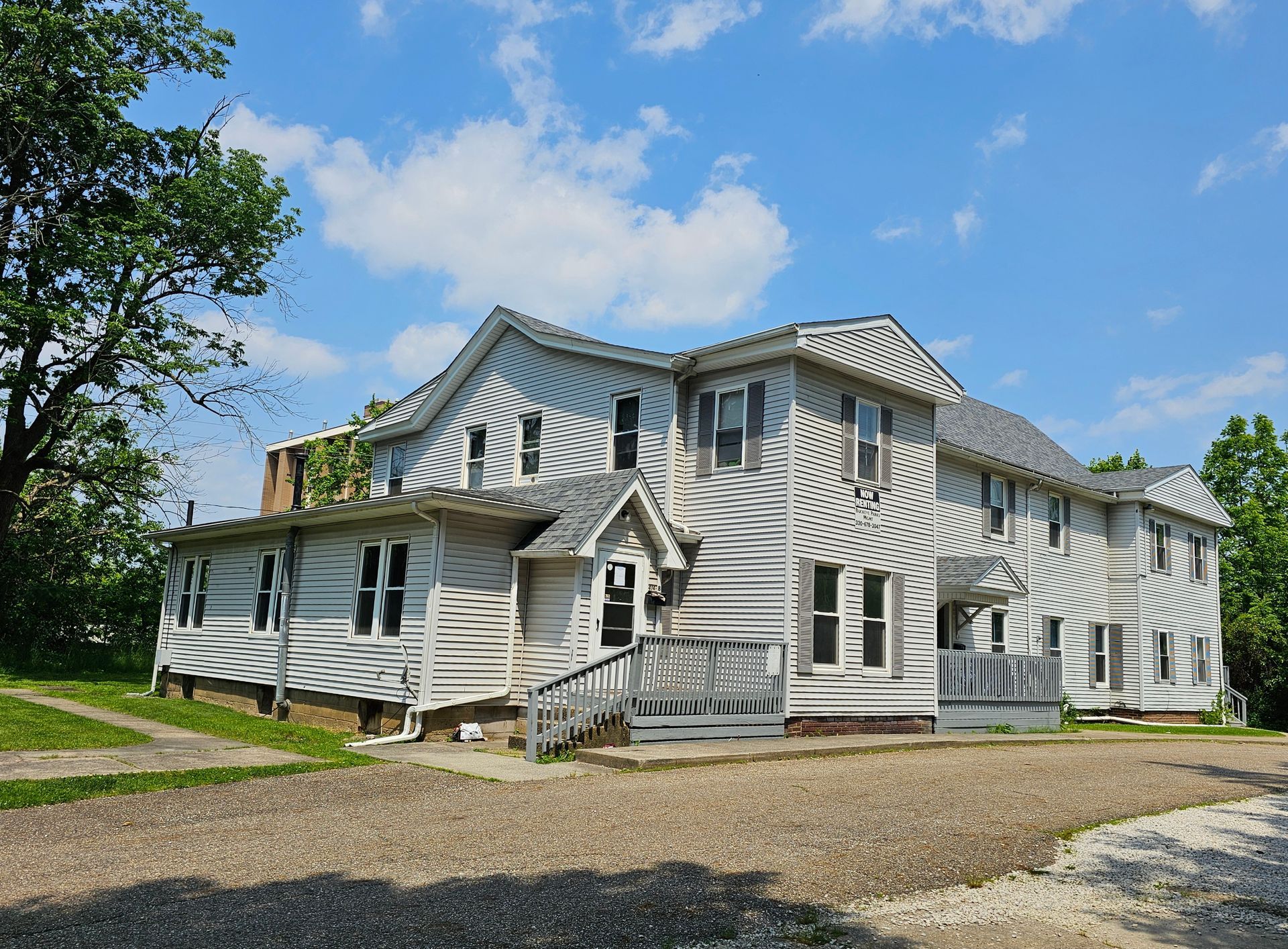 White striped two-story house with porch and gabled roof under a blue sky