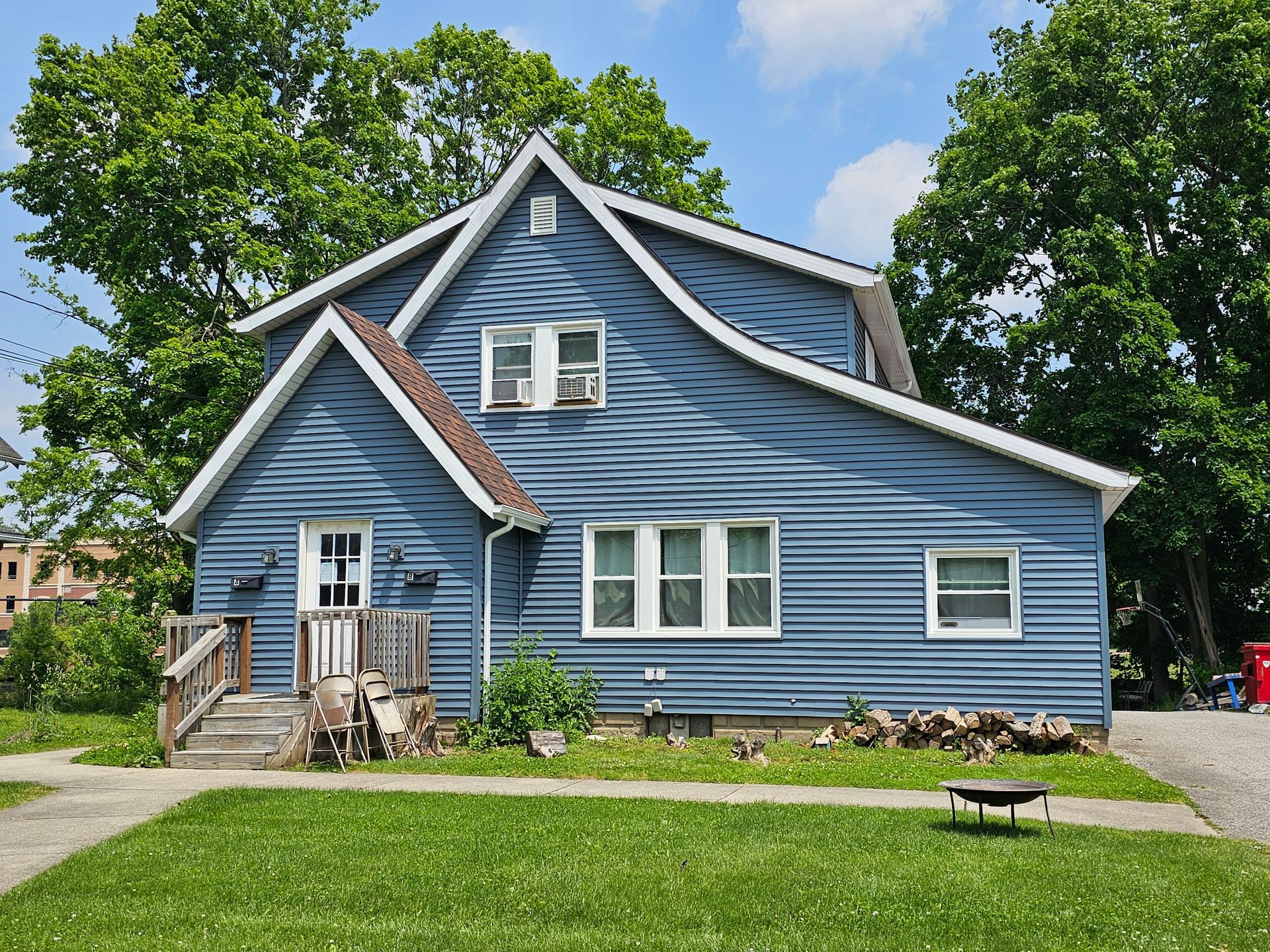 Blue two-story house with white trim and a front lawn under a partly cloudy sky