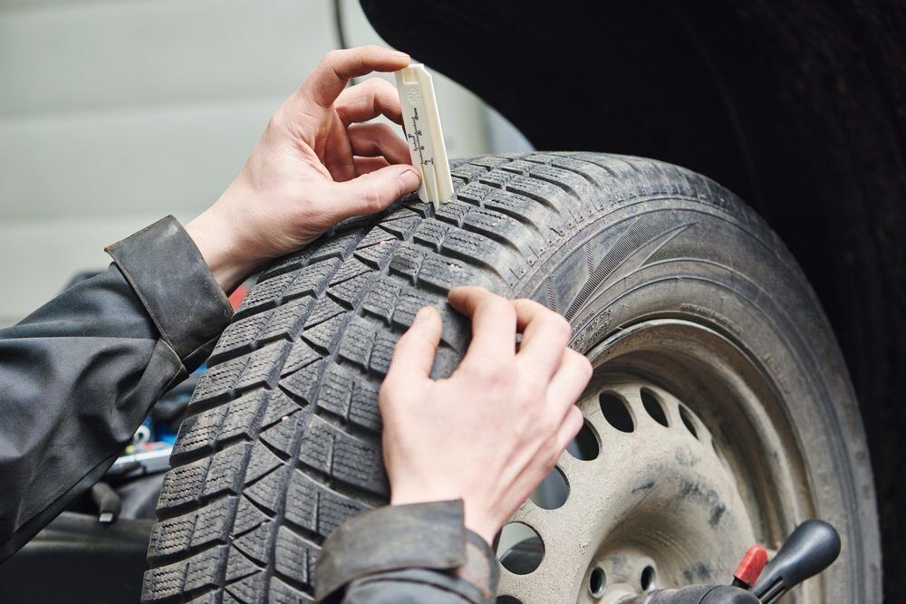 A Person is Measuring the Depth of a Tire With a Tape Measure โ Auto Repair Solutions Unanderra In Unanderra, NSW