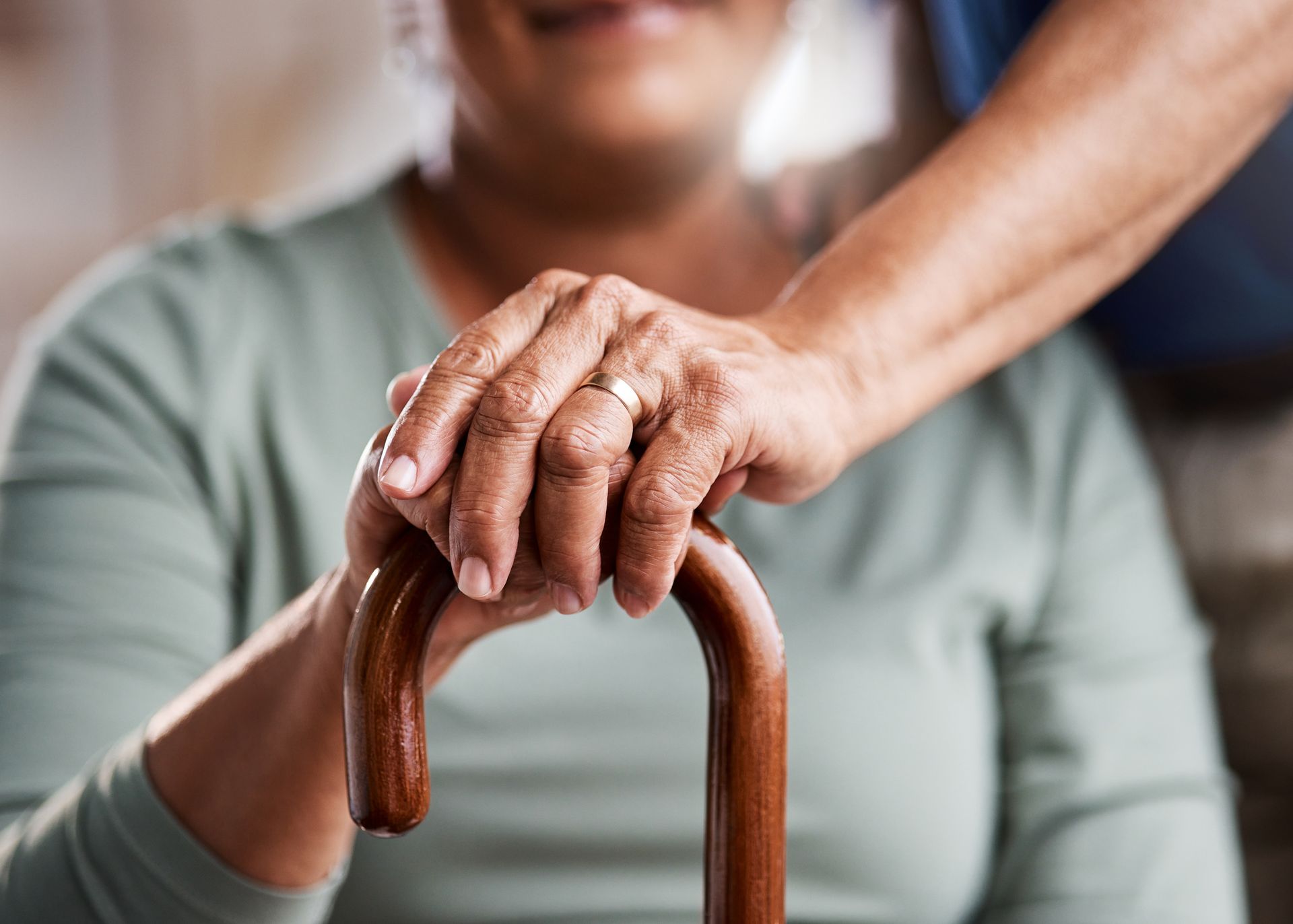 A man is holding the hand of an elderly woman holding a cane.