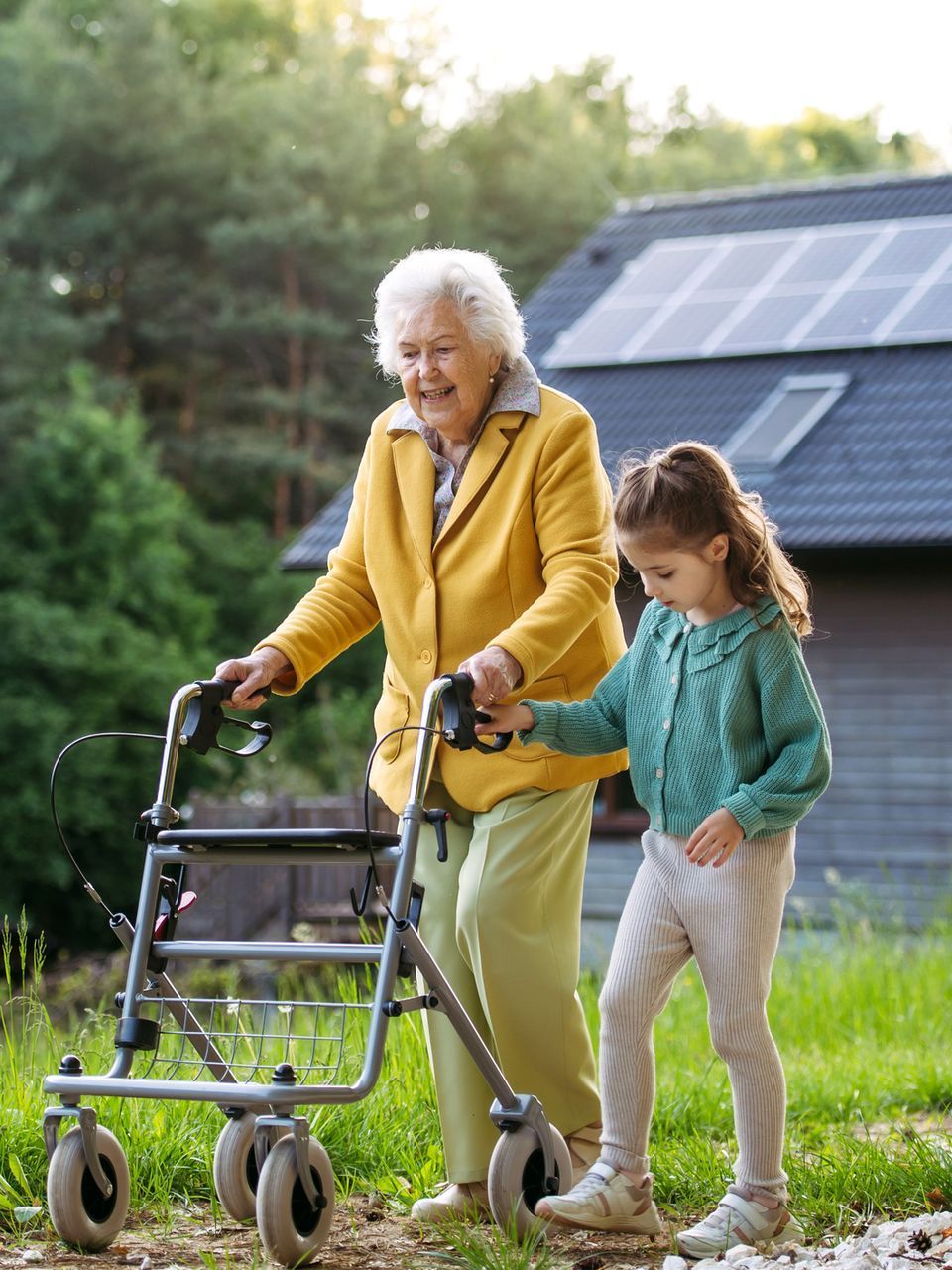 An elderly woman with a walker is being helped by a little girl.