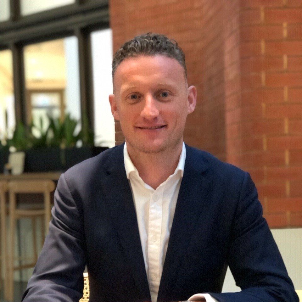 A man in a suit and white shirt is sitting at a table