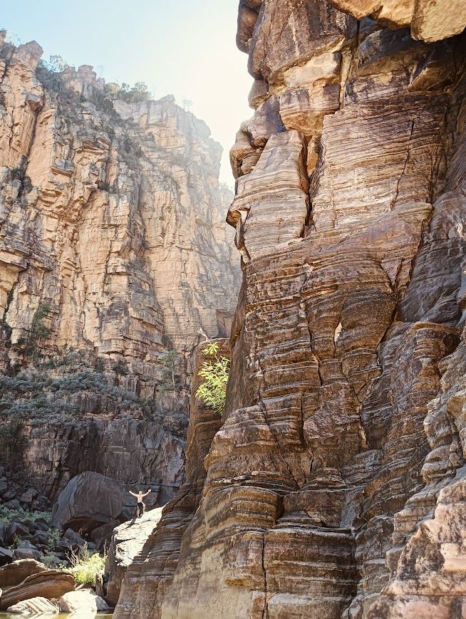 Rocky canyon with sunlight. Brown, layered rock formations frame a narrow passage  — NT Driver Guide - Escorted Tours & Transfers in Darwin City, NT