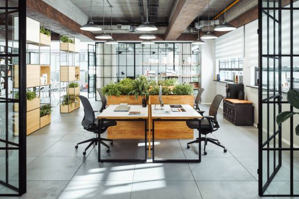 A modern office with a lot of windows and tables and chairs.