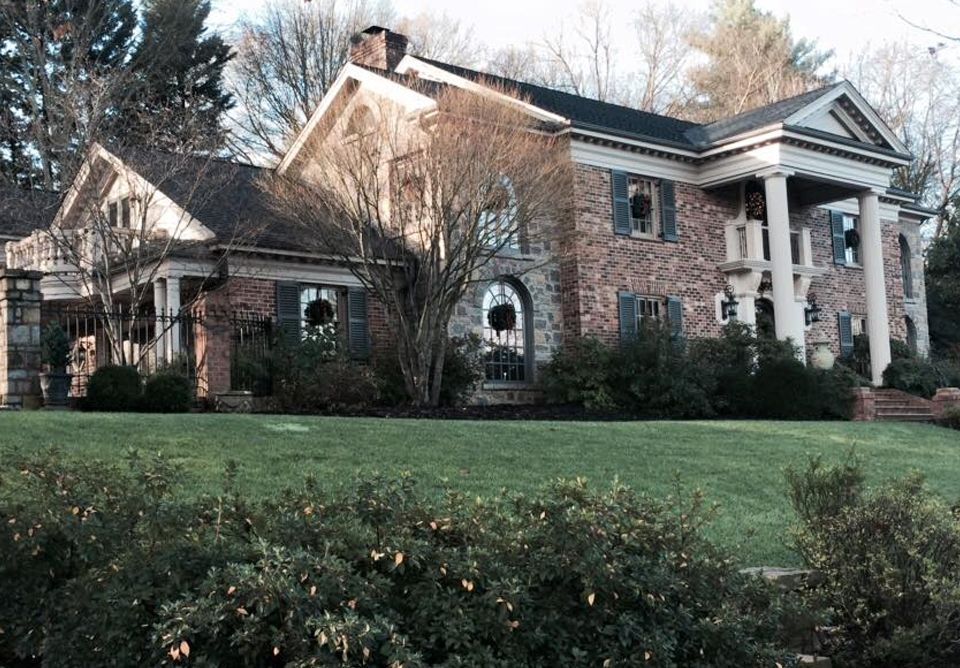 Large brick house with white columns and a manicured lawn in front.