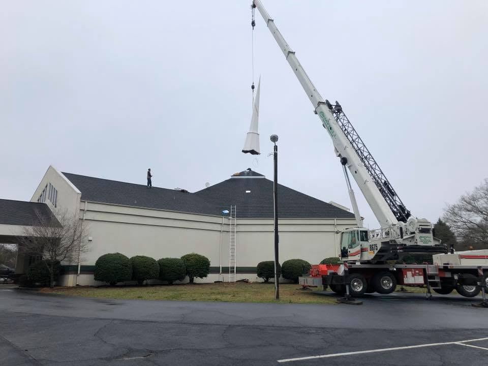Church building with tall white steeple and gray roof in a suburban area under cloudy skies