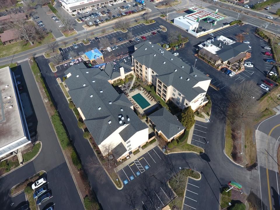 Aerial view of a large beige apartment complex with parking lots, trees, and a central courtyard.