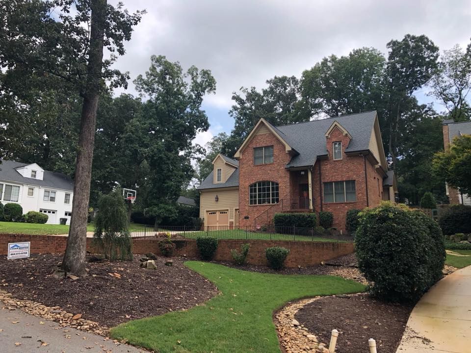 Brick house with manicured lawn and landscaped front yard in a suburban neighborhood.