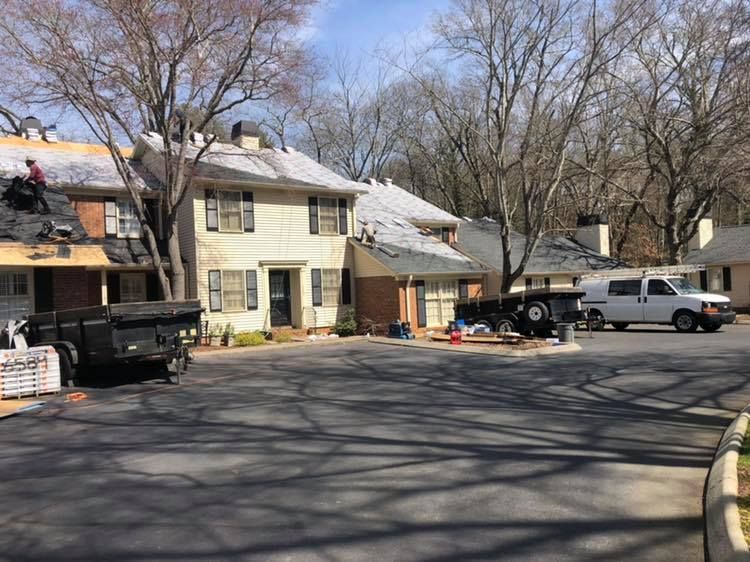 Residential building and parked vehicles beside a tree-lined driveway on a sunny day