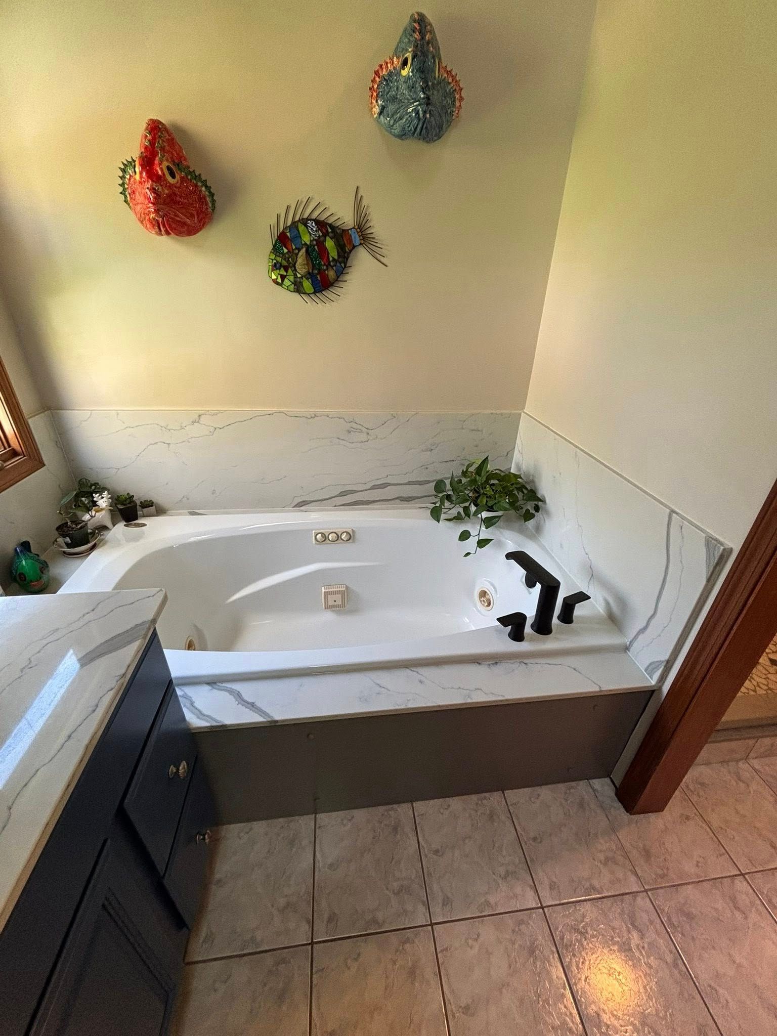 Small bathroom with a white jetted tub, tiled floor, and colorful wall decor above it.
